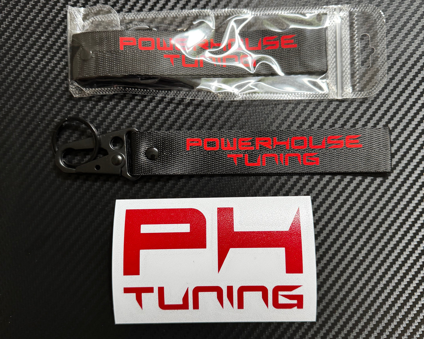 PowerHouse Tuning keychain—19 cm black fabric tag with bold red printed 'PowerHouse Tuning' text, attached to a metal key ring and spring buckle.